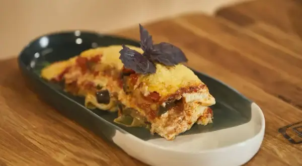 Pyszna lasagne z bakłażanem i pomidorami, udekorowana bazylią. Idealna do podgrzania i szybkiego obiadu.