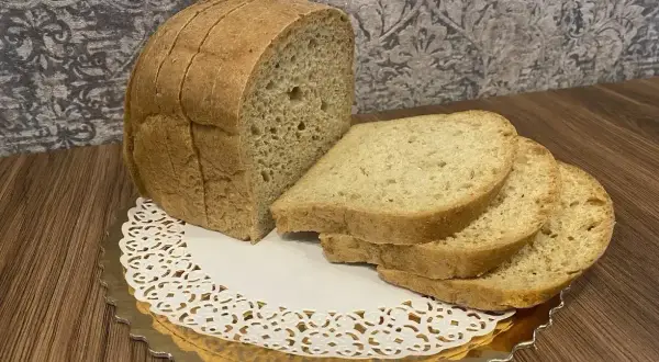 Chleb keto z mąki kokosowej, pokrojony w kromki, prezentuje się apetycznie na złotej podstawce.