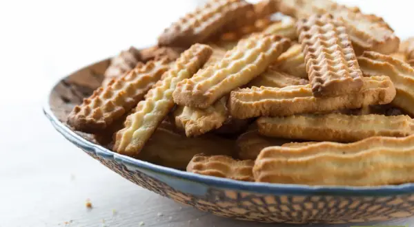 Stos ciasteczek na talerzu, idealnych do kawy. Prosty przepis na ciastka, który każdy może wypróbować.