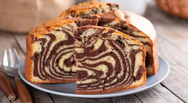 Proste ciasto zebra z czekoladowymi i waniliowymi wzorami, pokrojone na talerzu, gotowe do podania.