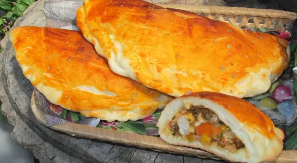 Złociste mini calzone z aromatycznym nadzieniem, ułożone na drewnianej desce.