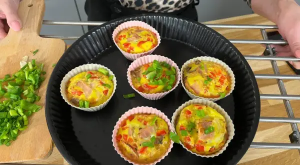 Sześć pysznych muffinek jajecznych z szynką, papryką i szczypiorkiem, gotowych do podania.