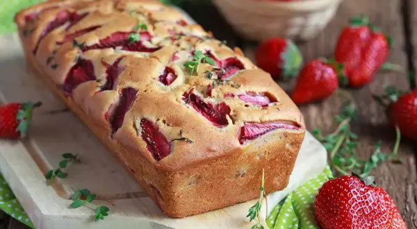 Pyszne ciasto z owocami, z kawałkami truskawek w cieście, ozdobione świeżymi ziołami. Idealne na letnie popołudnie.