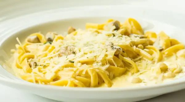 Tagliatelle z grzybami w kremowym sosie, posypane parmezanem. Pyszny sos cebulowy podkreśla smak dania.