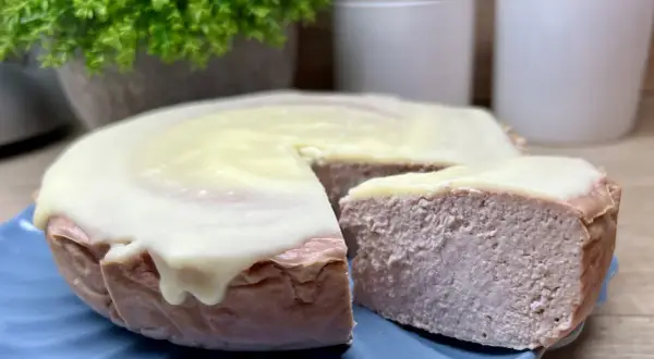 Pyszny sernik z malinami i białą czekoladą, z kawałkiem odciętym do degustacji.