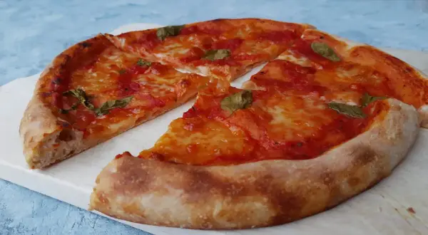 Pyszna pizza na zakwasie z pomidorami i mozzarellą, ozdobiona listkami bazylii. Idealna na każdy dzień.