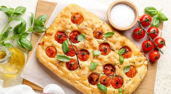 Pyszna focaccia z pomidorkami koktajlowymi i bazylią, idealna do pesto.