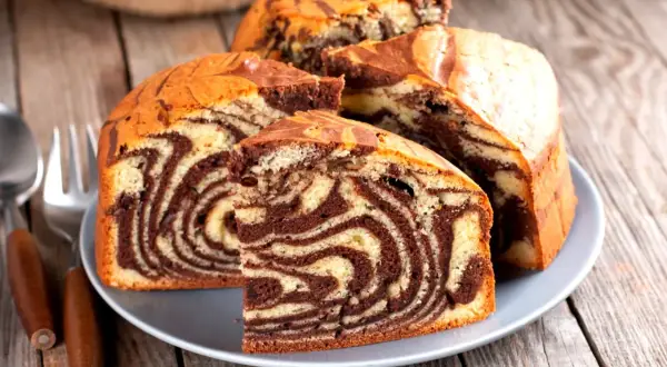 Pyszna babka marmurkowa z czekoladowymi i waniliowymi wzorami, pokrojona na talerzu, gotowa do degustacji.