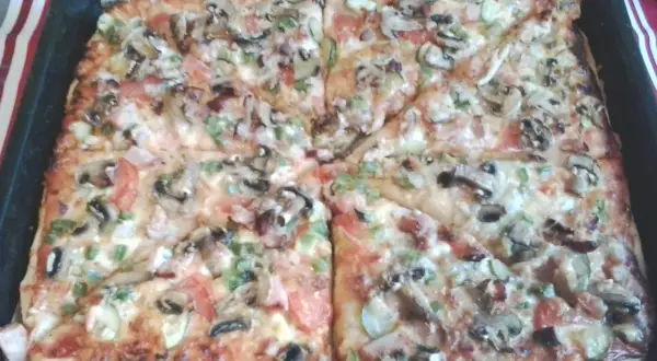 Pyszna pizza na grubym cieście z pieczarkami, pomidorami i papryką, prosto z blachy. Idealna na rodzinny obiad.