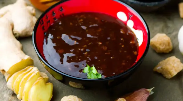 Miseczka z sosem teriyaki, obok świeży imbir, czosnek i cukier. Idealne składniki do sosu teriyaki przepis.