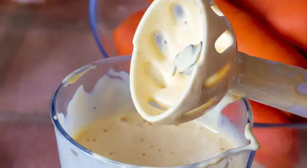 Kremowy majonez powstaje w szklanym naczyniu, gdy blender zanurza się w jego gładkiej masie. Idealny majonez przepis w zasięgu ręki.