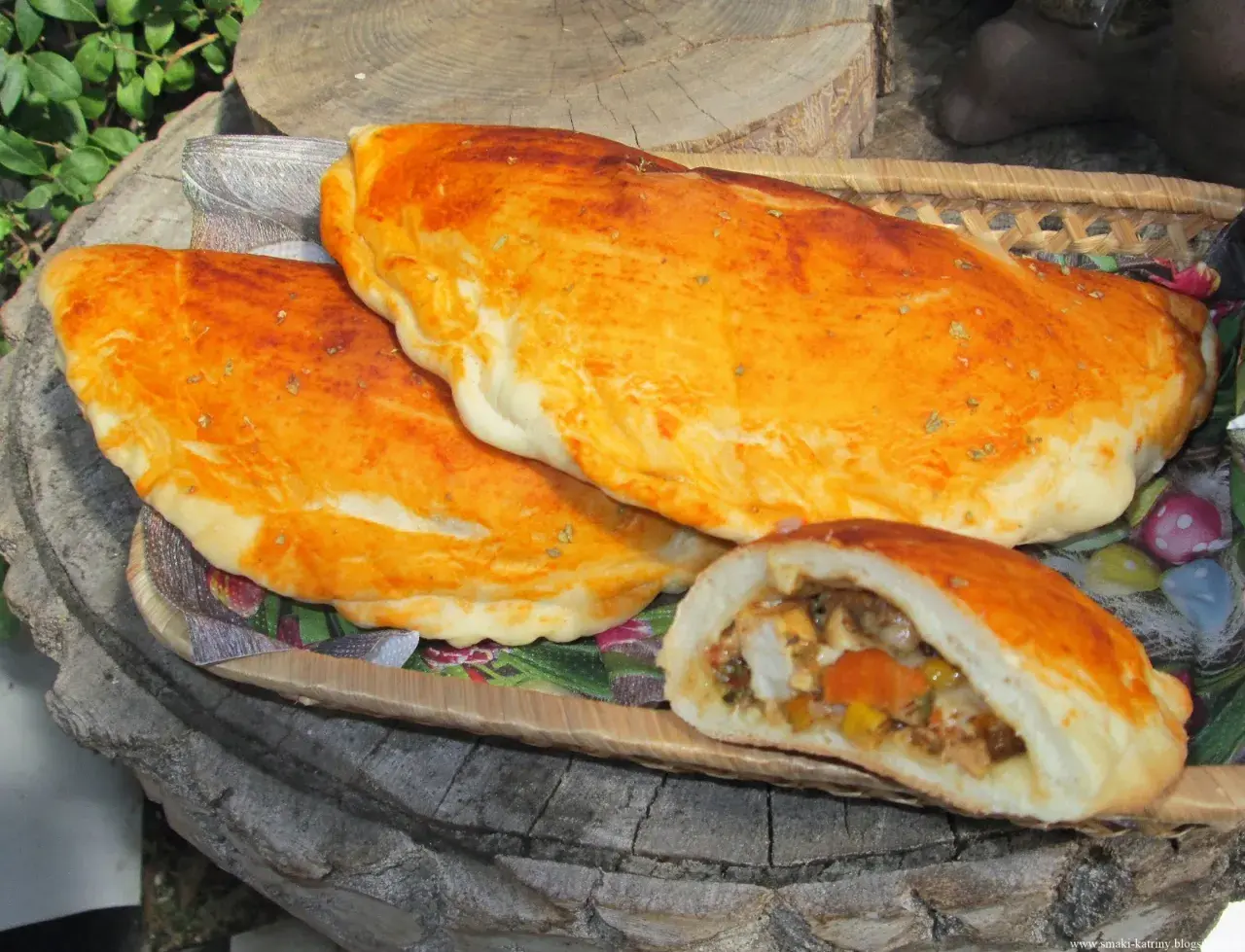 Złociste mini calzone z aromatycznym nadzieniem, ułożone na drewnianej desce.