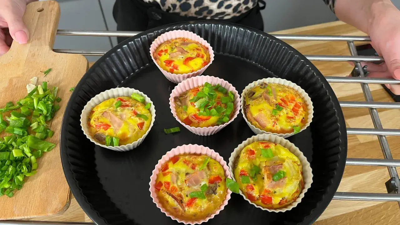 Sześć pysznych muffinek jajecznych z szynką, papryką i szczypiorkiem, gotowych do podania.