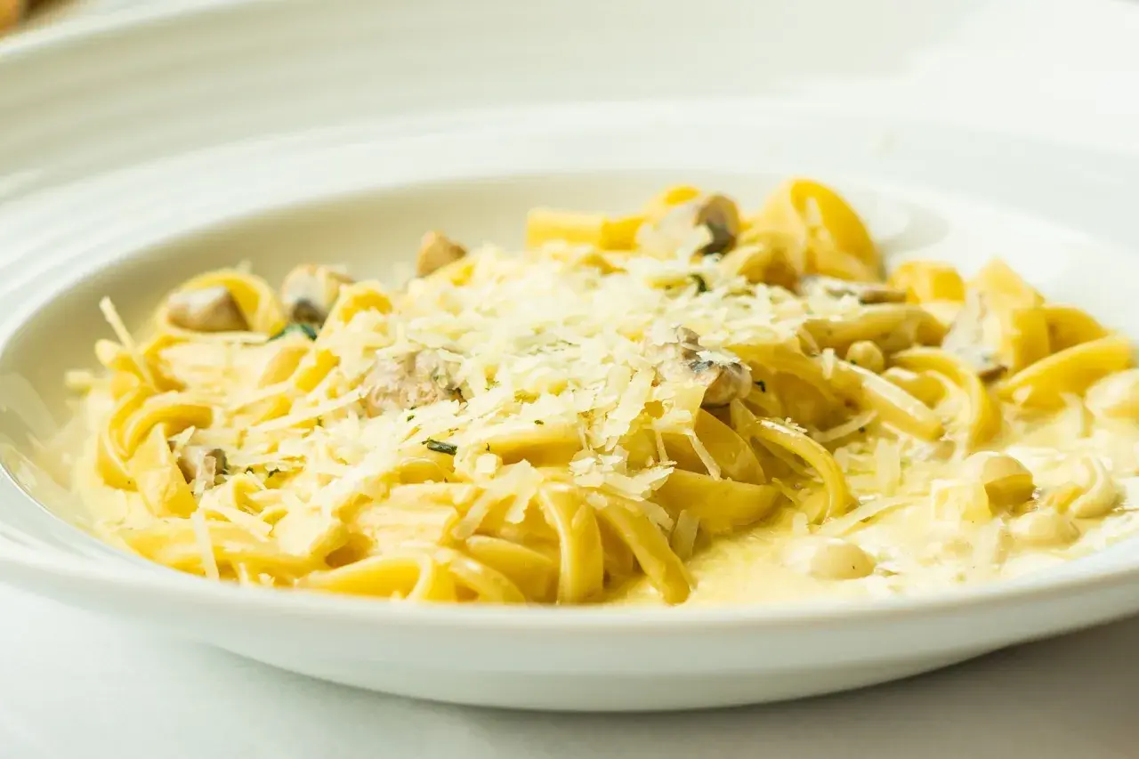 Tagliatelle z grzybami w kremowym sosie, posypane parmezanem. Pyszny sos cebulowy podkreśla smak dania.