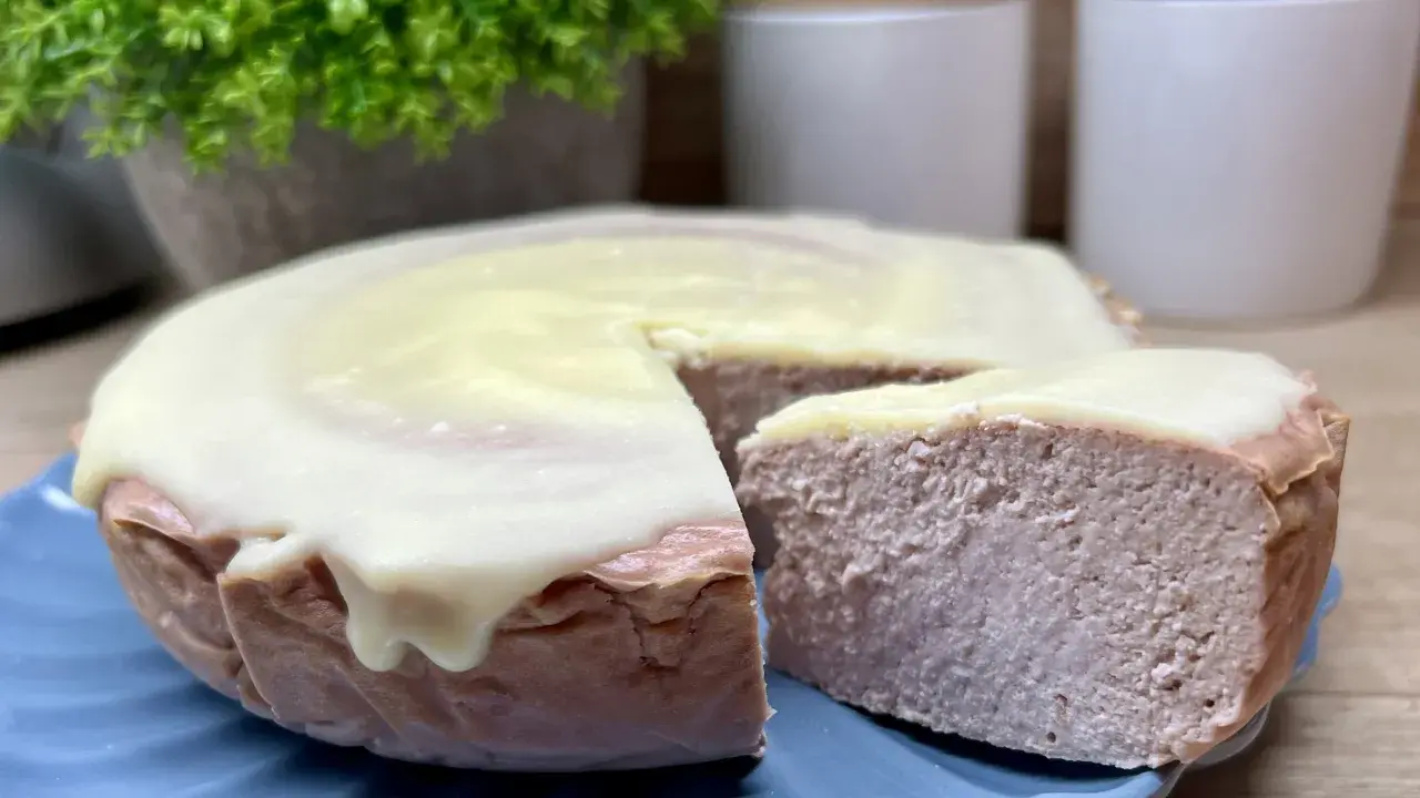 Pyszny sernik z malinami i białą czekoladą, z kawałkiem odciętym do degustacji.