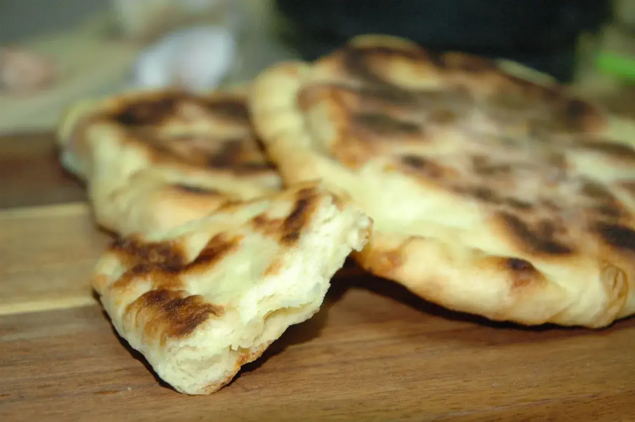 Puszyste chlebki naan z Thermomixa, lekko przypieczone, gotowe do podania.