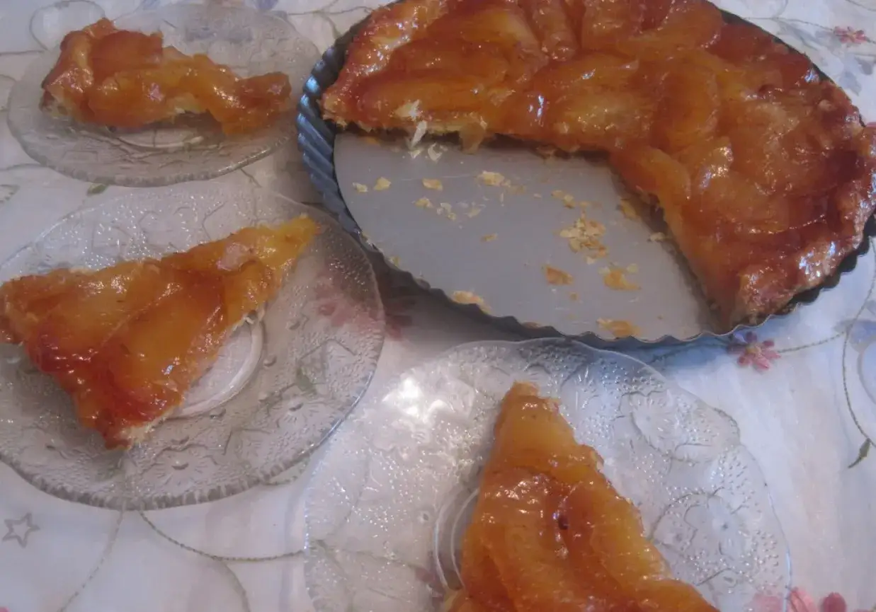 Apetyczna tarta tatin z karmelizowanymi jabłkami, częściowo wyjęta z formy, podana na talerzykach.