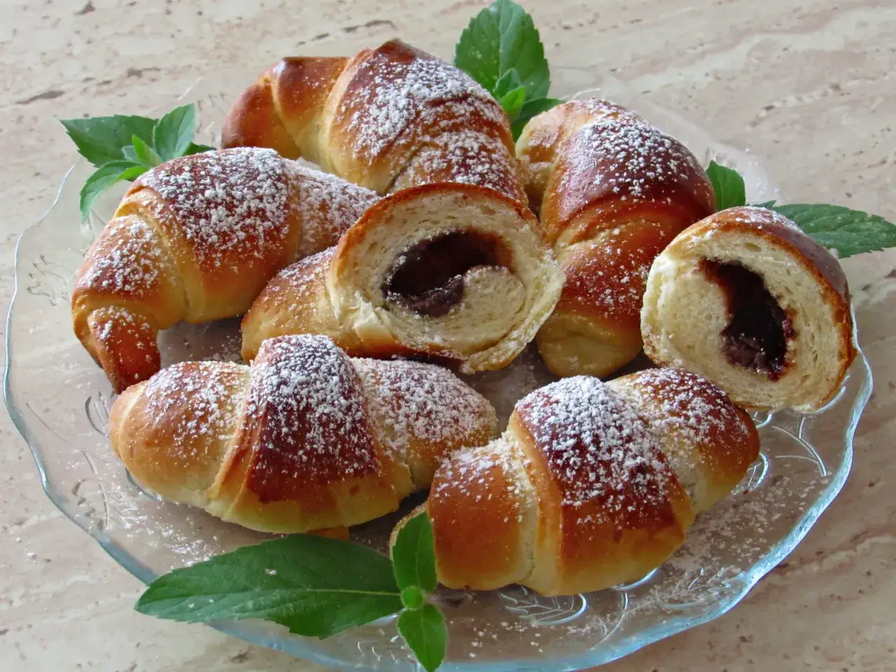 Pyszne rogaliki z czekoladą, posypane cukrem pudrem, kuszą swoim wyglądem. Idealne na deser lub śniadanie.