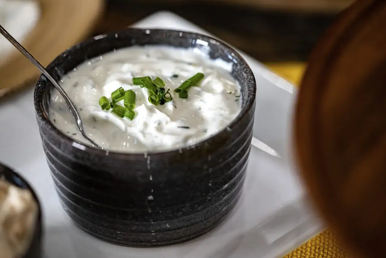 Kremowy sos tzatziki, udekorowany szczypiorkiem, czeka na podanie. Idealny dodatek do greckich potraw.