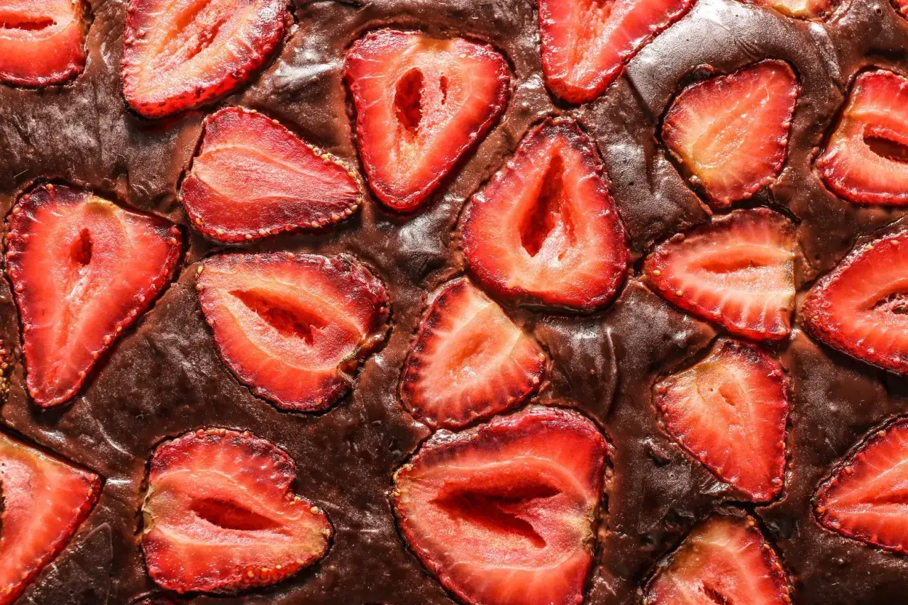 Czekoladowy brownie z kawałkami świeżych truskawek, tworzące apetyczny deser.