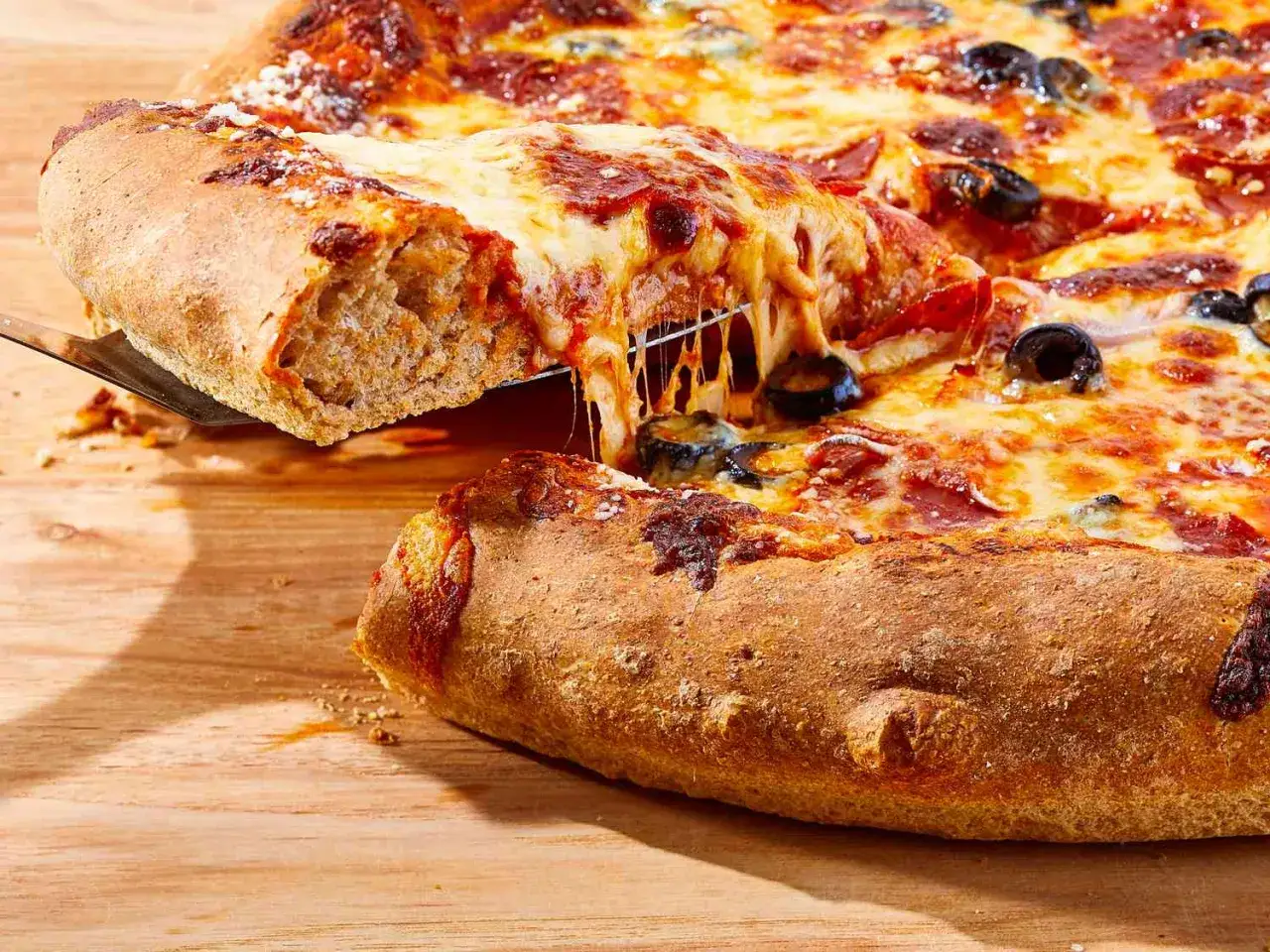 Pyszne, ciągnące się serowe ciasto na pizzę z mąki pełnoziarnistej, z pepperoni i oliwkami. Idealne na zdrowy obiad.