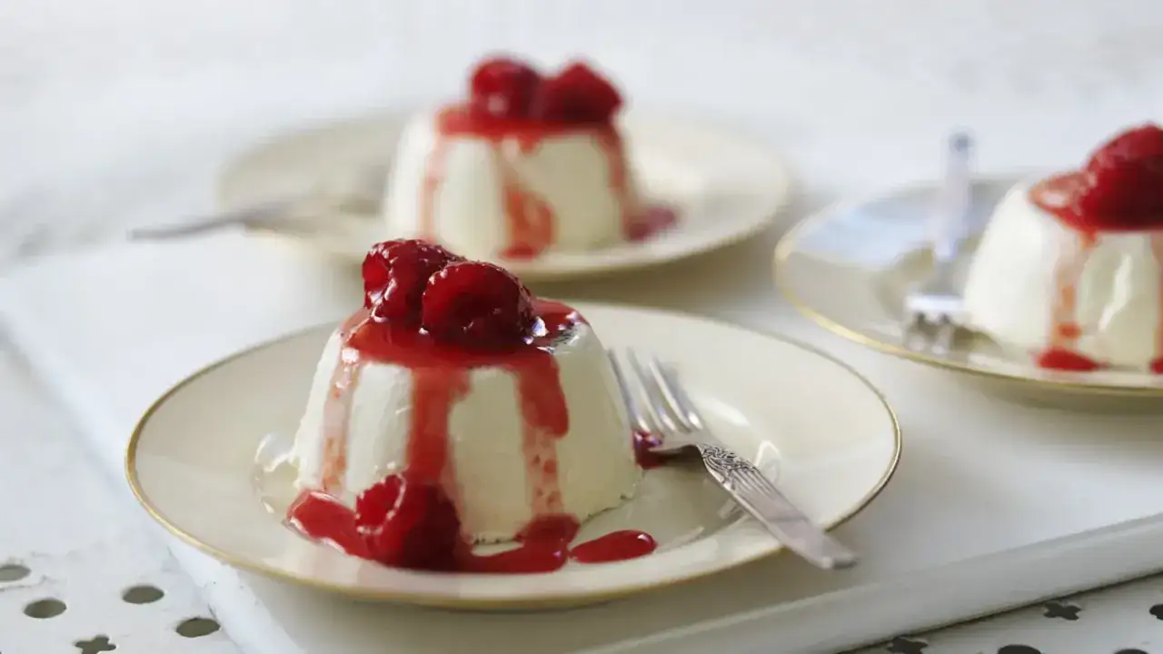 Pyszna panna cotta z malinami i sosem malinowym na talerzyku.