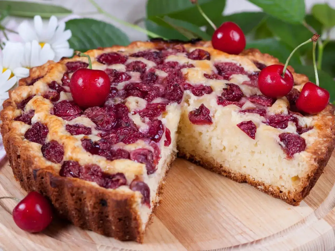 Pyszne ciasto z czereśniami, z rumianą skórką i soczystymi owocami, ozdobione świeżymi czereśniami.
