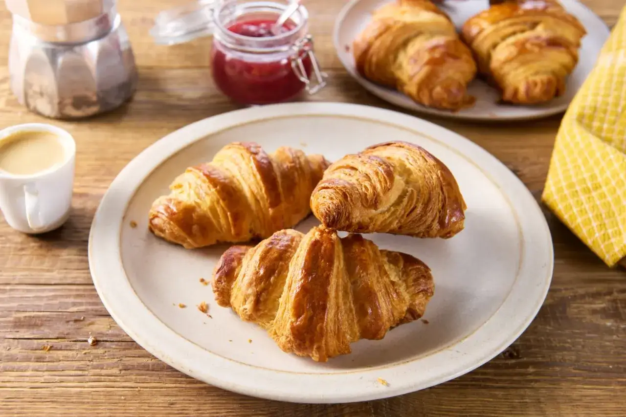 Złociste croissanty, idealne na śniadanie. Ten przepis na croissanty to gwarancja sukcesu. Obok kawa, dżem i mokka.
