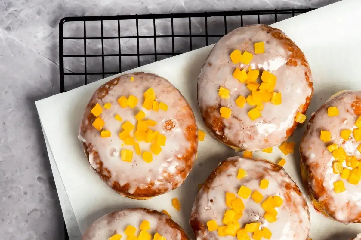 Pączki z piekarnika, oblane lukrem i posypane kandyzowaną skórką pomarańczową, kuszą swoim wyglądem.
