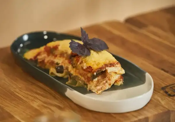 Pyszna lasagne z bakłażanem i pomidorami, udekorowana bazylią. Idealna do podgrzania i szybkiego obiadu.