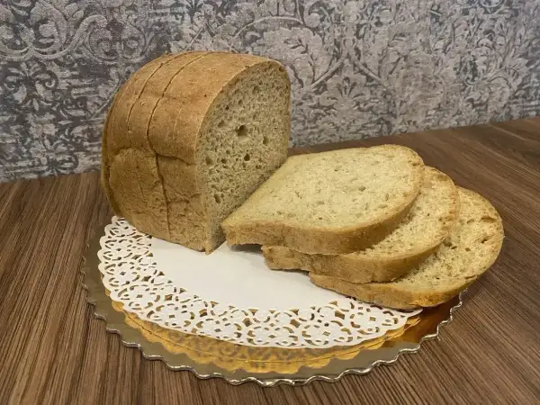 Chleb keto z mąki kokosowej, pokrojony w kromki, prezentuje się apetycznie na złotej podstawce.