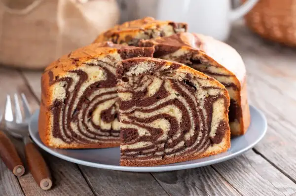 Proste ciasto zebra z czekoladowymi i waniliowymi wzorami, pokrojone na talerzu, gotowe do podania.