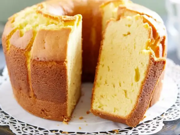 Puszysta babka pomarańczowa, zrumieniona na zewnątrz, z widocznym kawałkiem ciasta. Idealna na popołudniową herbatę.