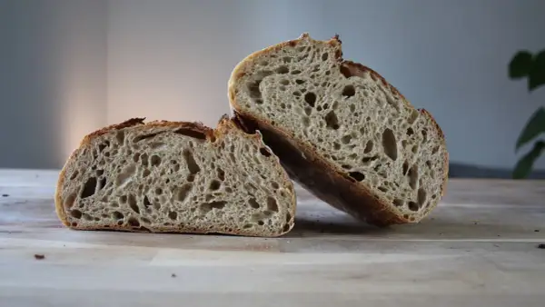 Puszysty chleb żytni, przekrojony na pół, z widocznym, porowatym wnętrzem i chrupiącą skórką.