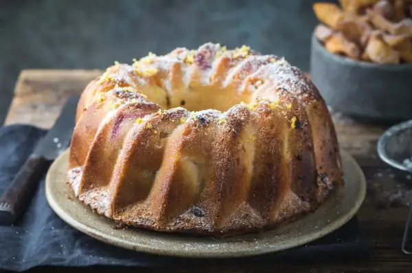 Złocista babka piaskowa, oprószona cukrem pudrem i skórką cytrynową, czeka na talerzu, by umilić popołudnie.
