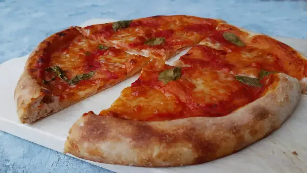 Pyszna pizza na zakwasie z pomidorami i mozzarellą, ozdobiona listkami bazylii. Idealna na każdy dzień.