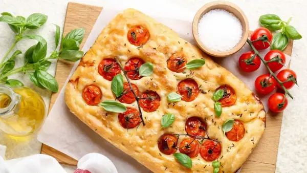 Pyszna focaccia z pomidorkami koktajlowymi i bazylią, idealna do pesto.