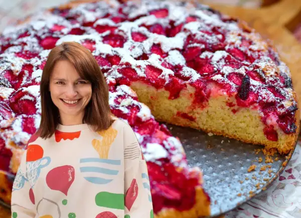 Uśmiechnięta kobieta obok pysznego, szybkiego ciasta z truskawkami, posypanego cukrem pudrem.
