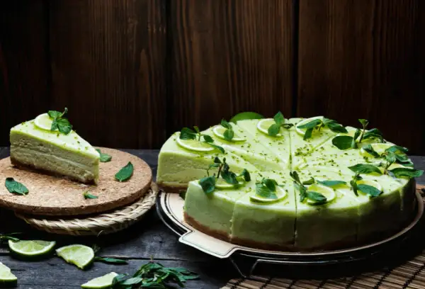 Zielony sernik pistacjowy, udekorowany plasterkami limonki i miętą, wygląda apetycznie.