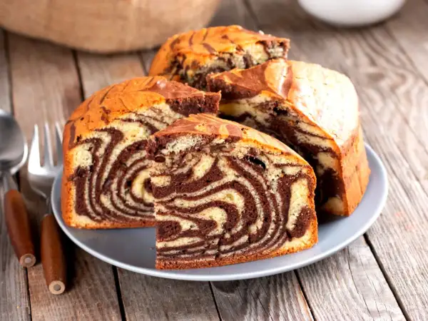 Pyszna babka marmurkowa z czekoladowymi i waniliowymi wzorami, pokrojona na talerzu, gotowa do degustacji.