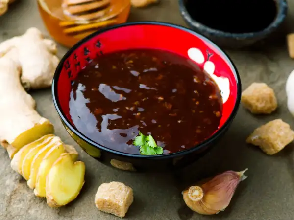 Miseczka z sosem teriyaki, obok świeży imbir, czosnek i cukier. Idealne składniki do sosu teriyaki przepis.